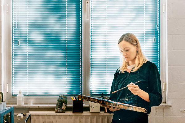 portrait of female artist painting in workshop near window