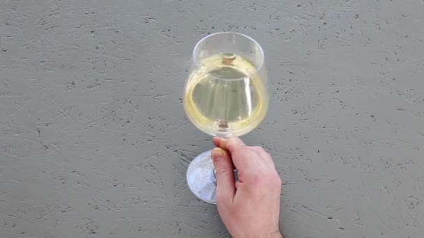 男性手捧一杯白葡萄酒在灰色混凝土背景 — 图库视频影像