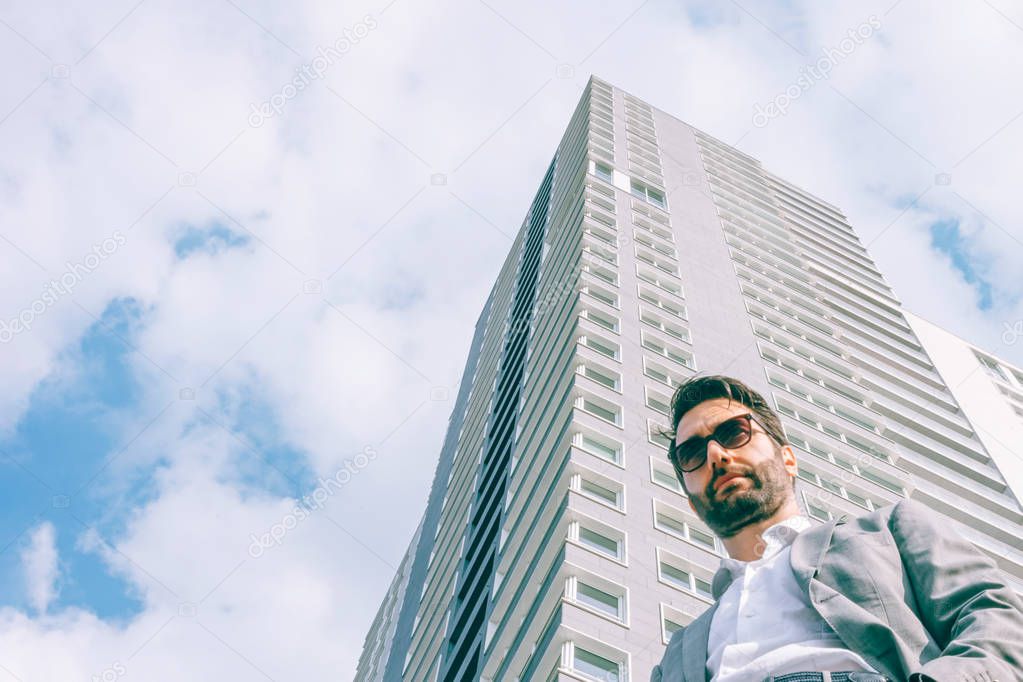 portrait of a businessman seen from below in front of a skyscraper. The sky is the limit.
