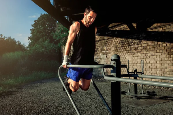 boxer athlete in outdoor training doing pushups at the dip station. sport, healthy life and strength concept