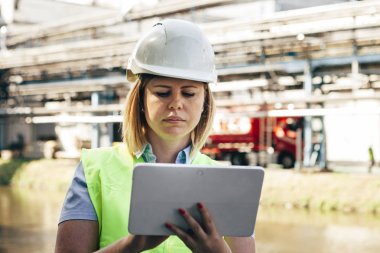 bir tablet tutan bir fabrikada kadın işçi açık havada. kadın meslekleri ve endüstriyel işler kavramı