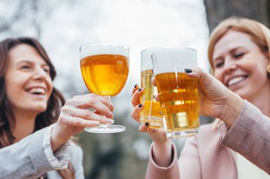 sonbaharda bir açık hava terasında oturan üç kadın, konuşma, gülme ve bira ile birlikte tost.