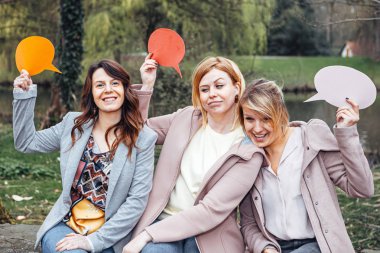 parkta kız bir grup ellerinde bir düşünce balonu tutarken garip ifadeler yapıyor. Dostluk ve iletişim kavramı.