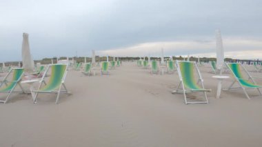 Yazın sonunda boş bir plajda güverte sandalyeleri arasında yürüyen pov insanı. 