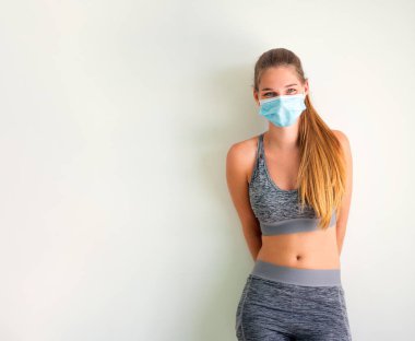 Tıbbi maskeli genç bir kadının portresi. Cvid virüsüne karşı koruyucu maskeli spor giysili bir kadın.