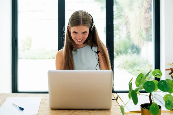Young business woman working at home with laptop and papers on desk, female student talking on conference call, one people watching webinar by webcam, online learning, teaching concept