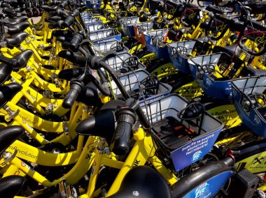 Bükreş, Romanya - 22 Temmuz 2020: Bükreş 'teki Herastrau Park yakınlarındaki bir bisiklet kiralama merkezinde Raiffeisen Bank logosuyla damgalanmış çok sayıda sarı bisiklet. Bu resim sadece editörler içindir..