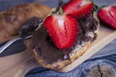 kruvasan çikolata makarna ve eski bir ahşap zemin üzerine çilek ile