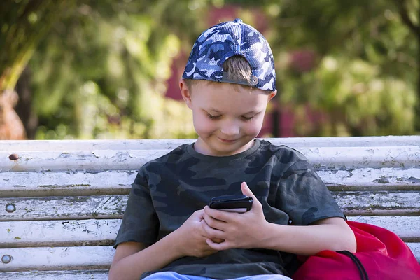 Carino Ragazzo Cercando Cellulare Panchina Estate — Foto Stock