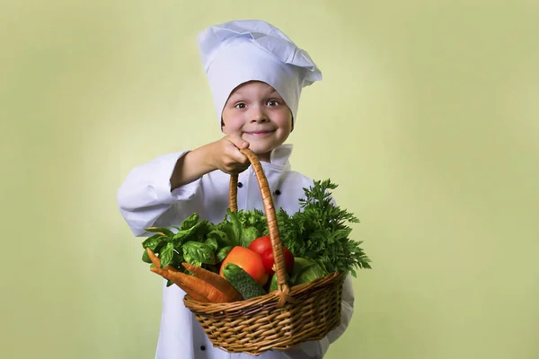 funny boy chef in uniform chef holding a basket of vegetables