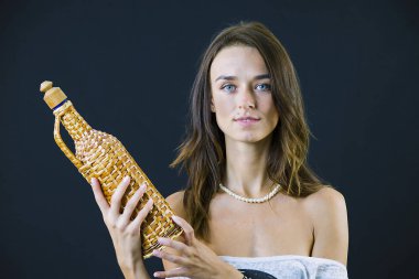 bir şişe şarap siyah bir arka plan üzerinde tutan şirin şık esmer kız