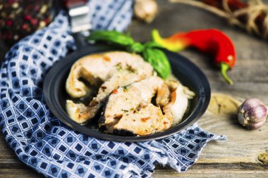 baharat ve ahşap bir masa üzerinde bir tavada baharatlı sos ile haşlanmış somon