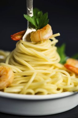 Spagetti karides etrafında siyah bir zemin üzerine bir çatal ile