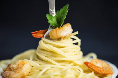Spagetti karides etrafında siyah bir zemin üzerine bir çatal ile