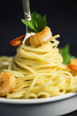 Spagetti karides etrafında siyah bir zemin üzerine bir çatal ile