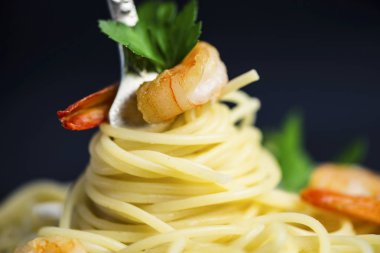 Spagetti karides etrafında siyah bir zemin üzerine bir çatal ile