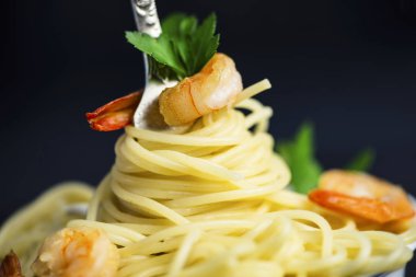 Spagetti karides etrafında siyah bir zemin üzerine bir çatal ile