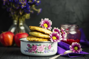 Çiçekler koyu ahşap arka plan üzerine bir kase kızarmış peynirli kek