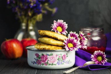 Çiçekler koyu ahşap arka plan üzerine bir kase kızarmış peynirli kek