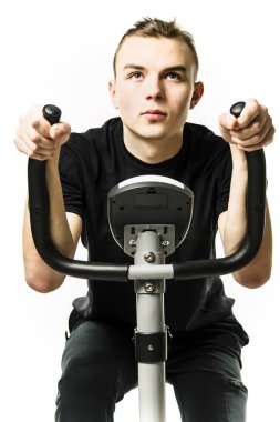 Genç adam beyaz bir arka plan üzerinde spor sabit bir bisiklet sürmek