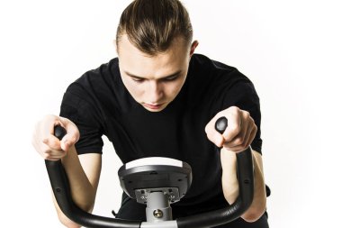 Genç adam beyaz bir arka plan üzerinde spor sabit bir bisiklet sürmek