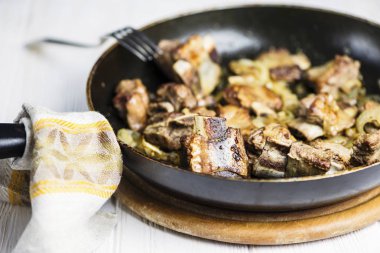 bir tavada soğanlı bir soslu kızarmış dana kaburga