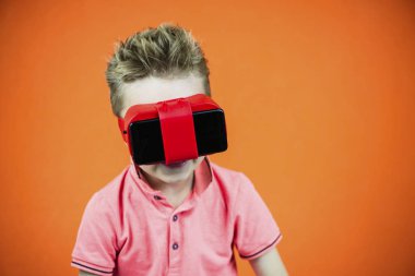 sanal gerçeklik bardaklarda smartphone üzerinde turuncu artalanda komik çocuk