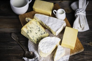 Camembert peyniri ve peynirler karanlık bir arka plan üzerinde ahşap bir gemide bir dizi