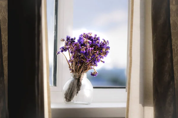 cute lilac wildflowers in a glass jar on a windowsill, background, vintage