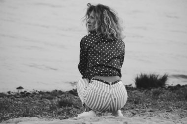 sevimli şık kıvırcık kız modeli oturur ve yaz aylarında nehir kıyısında rüyalar