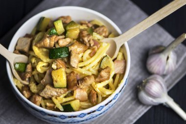koyu bir arka plan üzerinde bir kapta pastırma, et ve kabak ile carbonara makarna