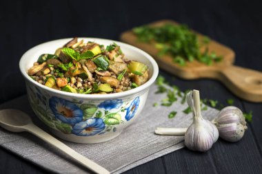 pastırma ve et ile haşlanmış karabuğday lapası, koyu bir arka plan üzerinde bir kapta yeşillik