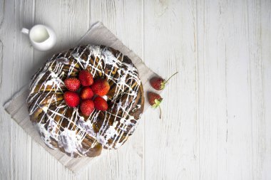 ahşap bir arka plan üzerinde beyaz dolgu, haşhaş tohumu ve çilek ile yuvarlak cupcake