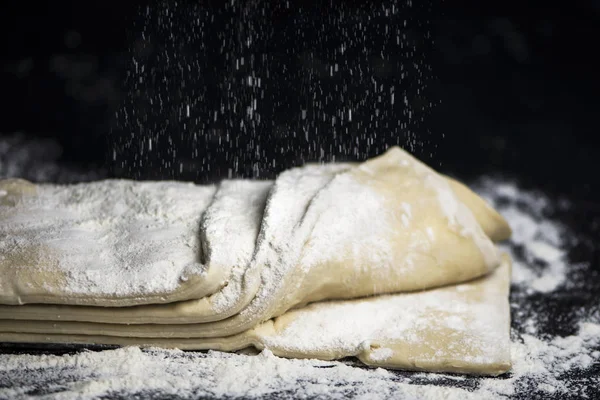暗い背景に小麦粉と生の酵母パフペーストリー — ストック写真