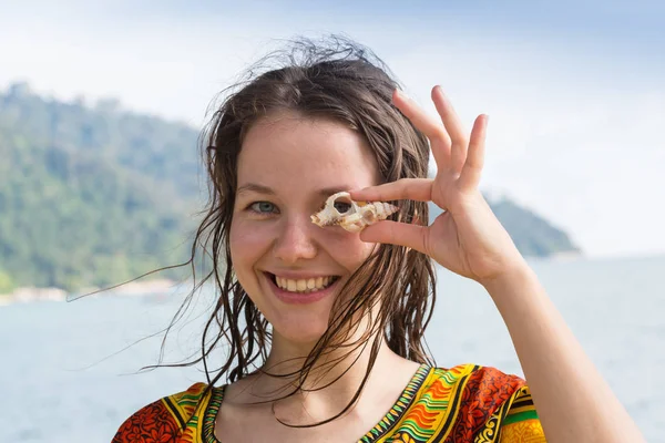 一个女孩在海洋风景的背景下拿着一只贝壳 — 图库照片