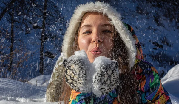 Schönheit Winter Mädchen weht Schnee in frostigen Winter Park. Draußen. fliegende Schneeflocken. sonniger Tag. Gegenlicht. freudige Schönheit junge Frau hat Spaß im Winterpark. — Stockfoto