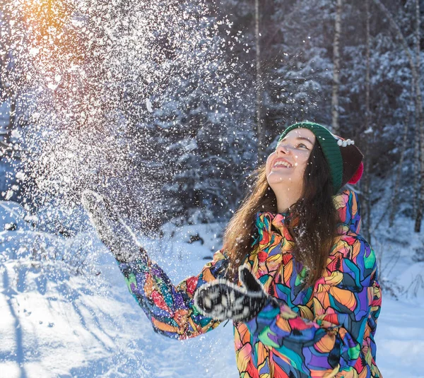 Весёлая зимняя веселая женщина бросает снежное знамя. Девочка, играющая на улице в снегу, смеется в желтом пальто, шляпе, перчатках и шарфе . — стоковое фото
