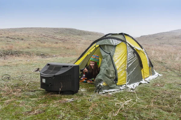 Kız niteliğine bir çadır içinde yatıyor ve eski bir Tv izliyor — Stok fotoğraf