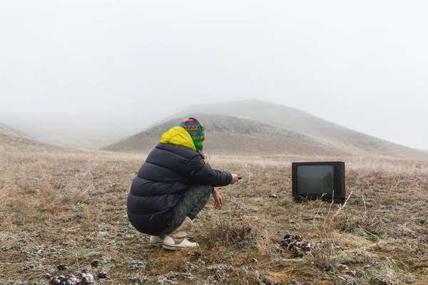 Menina na natureza deitada no chão e assistindo a uma TV velha — Fotografia de Stock