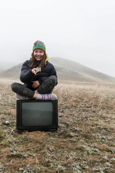 Meisje in de steppe zittend op de Tv. — Stockfoto