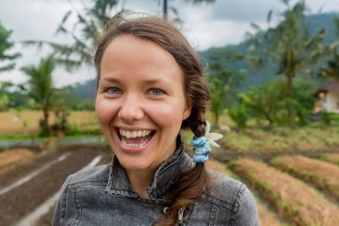 Parkta gülümseyen ve beyaz dişleriyle kameraya bakan bir kadın.