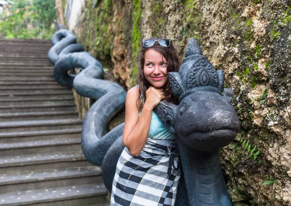 A girl looking at the sculpture of Naga, the Sanskrit and Pali word for a deity or class of entity or being taking the form of a very great snake — Stock Photo, Image