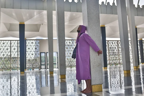 Um turista masculino na mesquita nacional da cidade de Kuala Lumpur fica perto da coluna e goza da beleza do interior . — Fotografia de Stock