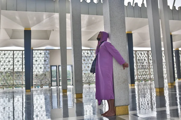 Ein männlicher tourist in der landesmoschee der stadt kuala lumpur steht neben der säule und genießt die schönheit des inneren. — Stockfoto