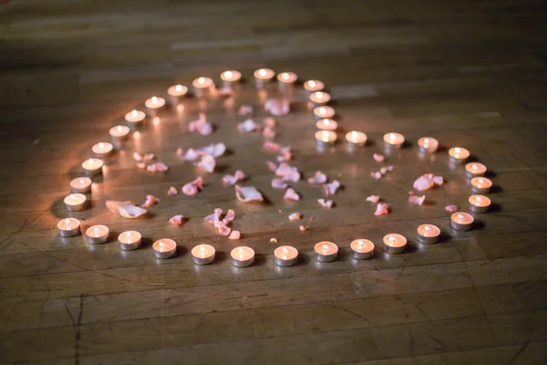 Silhueta do coração que é colocado com pequenas velas de chá no palco — Fotografia de Stock