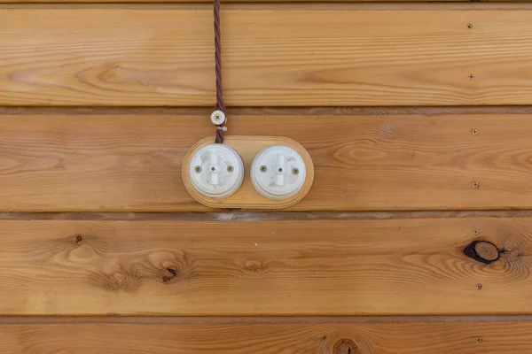 Electrical socket and switch in retro style on a wooden wall. Design of electricians in the house.