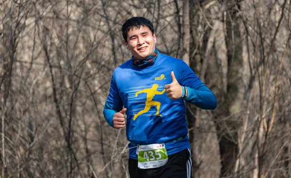 ALMATY, KAZAKHSTAN - 16 de marzo de 2019: retrato de un apuesto hombre maduro no identificado que corre por el bosque durante la maratón de primavera en la ciudad de Almaty, en el bosque que lleva el nombre de Baum en marzo. — Foto de Stock