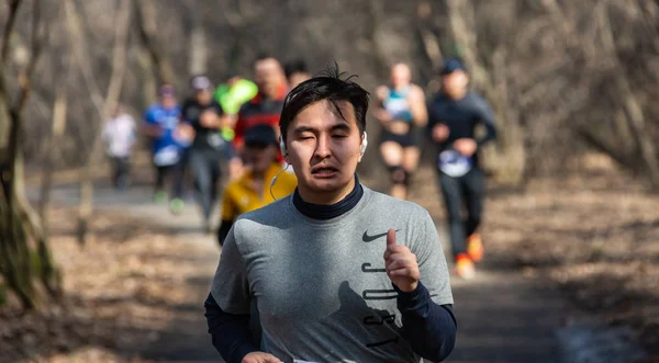 ALMATY, KAZAKHSTAN - 16 de marzo de 2019: retrato de un apuesto hombre maduro no identificado que corre por el bosque durante la maratón de primavera en la ciudad de Almaty, en el bosque que lleva el nombre de Baum en marzo. Fotos de stock