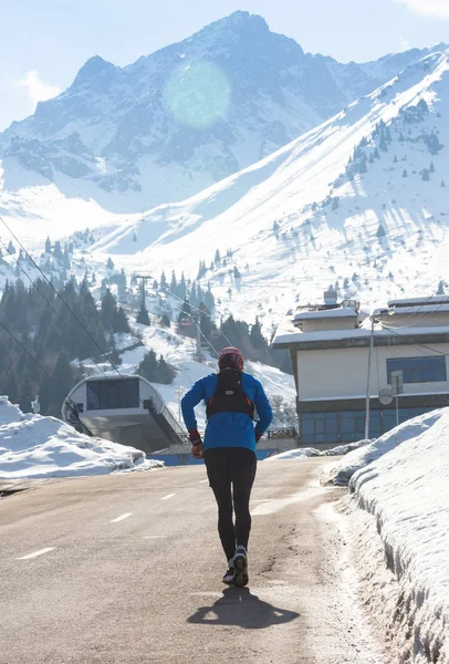 Człowiek młody, zdrowy sport działa na drogę asfaltową w górach śnieg w trail runner ciężkim treningu w koncepcji energii i wytrzymałości na tle pięknej zimy — Zdjęcie stockowe