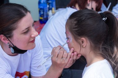 Almatı, Kazakistan - 10 Haziran 2018: Tanımlanamayan kız makyaj sanatçısı bir parlak karnaval yüz boyama Almatı Arena stadyum yakınında Yarkokros partisinde festival katılımcılara 10 Haziran yapar